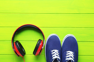 Headphones with shoes on a green wooden table, close up