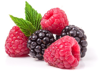 pile of raspberries and blackberries with leaves isolated on white background