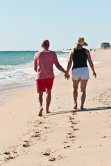 Older couple walking on an barrier island beach in the north atlantic on a sunny, windy fall day