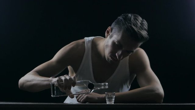 depressed man drinking vodka in a dark room