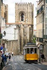 Lisbon street with the typical yellow tram and Lisbon Cathedral