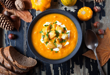 Pumpkin and carrot soup with cream and crackers, croutons for Thanksgiving, halloween. On dark old...