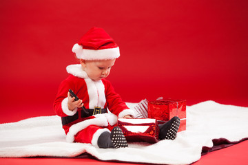 Beautiful little baby celebrates Christmas. New Year's holidays. with gift and the phone