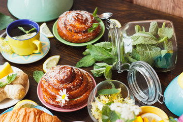 Cup with green tea, lemon and baked goods on the wooden background