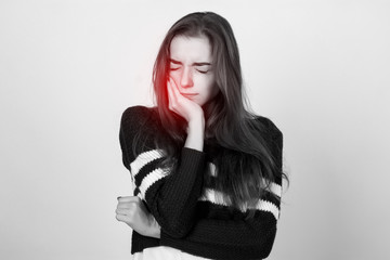 Portrait of a pretty woman  in short sweater, white shirt having toothache  standing over gray background black and white with red accent