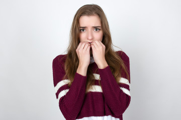 Portrait of a pretty woman  in short sweater shirt, white  with  fear face standing over gray background and looking at camera