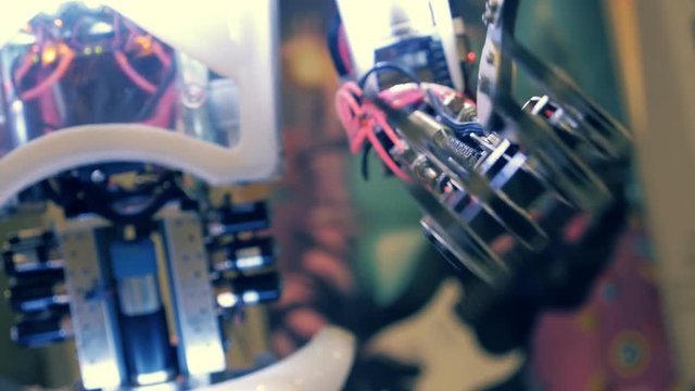 Humanoid robot from metal lowers his arm and moves fingers