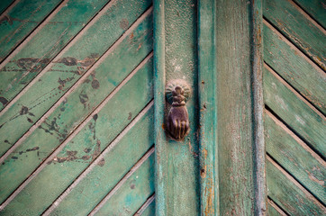 Old wooden door and a vintage door handle shaped as a hand, captured in old part of Tirana, Albania.