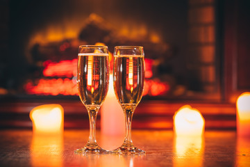 Beautiful Two glasses of champagne on blurred background with candles and a fireplace. The idea for postcards. Soft focus. Shallow DOF