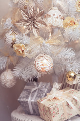 Fototapeta na wymiar Gift boxes lying under decorated white Christmas tree. New Year scene. Winter decoration