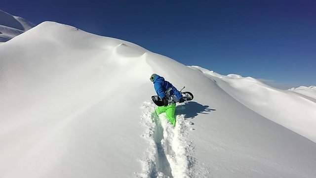 Freeride snowboarder hiking uphill in snowy mountains to ride fresh powder snow