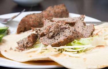 A minted lamb kofte kebab on a flatbread with salad