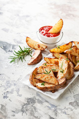 Roasted potato wedges with rosemary and tomato sauce, selective focus