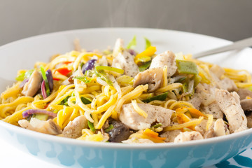 Close-up view of stir-fried chicken and vegetables served with noodles