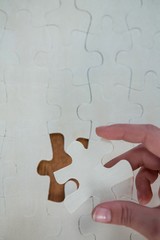 Woman placing missing piece in Jigsaw puzzle