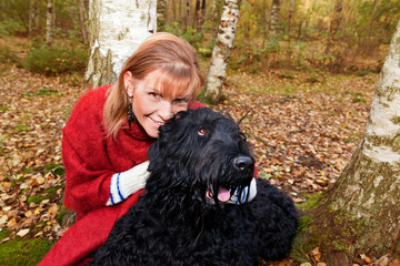 Young woman in a red poncho and Black Russian Terrier dog in aut