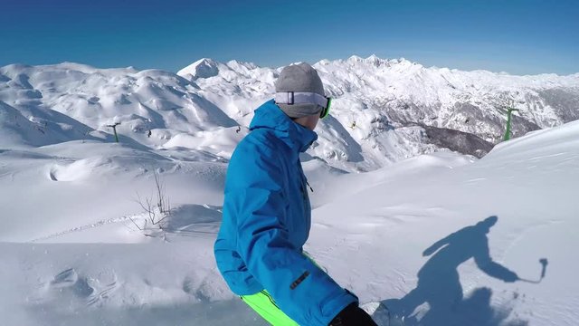 SELFIE: Extreme freeride snowboarder riding powder snow off-piste in mountains