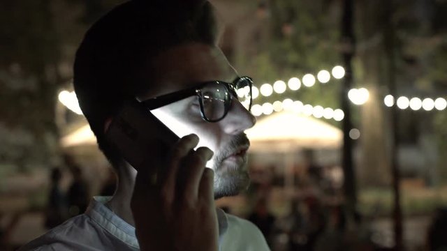 Man talking in darkness on cellphone, steadycam shot