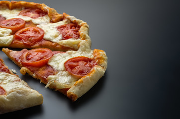 Slice delicious fresh pizza on a dark background.