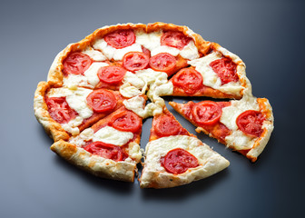 Sliced pizza margarita on dark metal background.