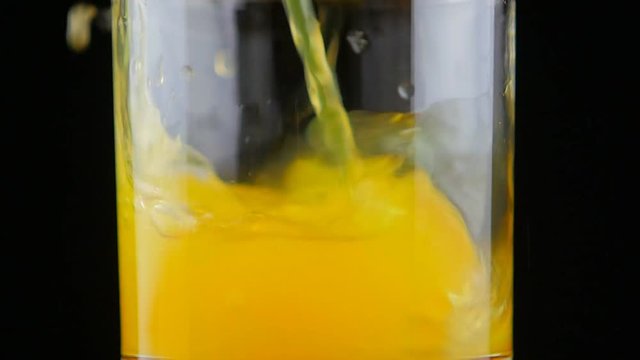 Pouring orange juice soda in glass in slow motion
