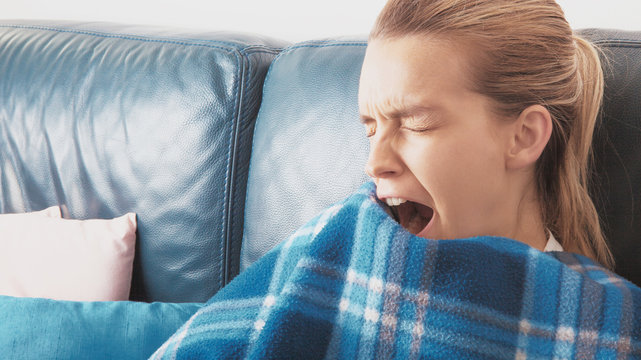Donna sbadiglia stanca sul divano con coperta