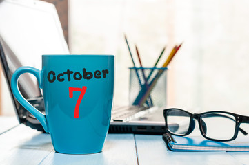 October 7th. Day 7 of month, Morning coffee blue cup with calendar on chief workplace background. Autumn time. Empty space for text
