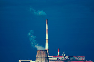 Power plant with two smoking chimney in front of blue sky. Cooling tower of power-plant against the...