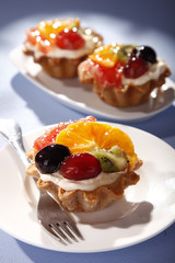 Short pastry with fruit, muffin - sweets for dessert - grape, tangerine, orange, kiwi, cream and whipped cream 