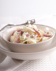 Pasta Carbonara with bacon, ham and cheese on white plate 