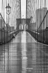 Brooklyn Bridge  on a rainy day with a lone walking personmonochrome