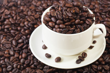 Coffee beans in a white cup on a pile of coffee bean background