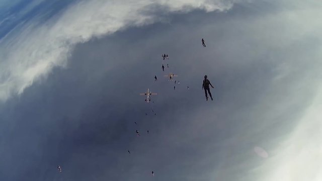Skydivers jump from airplanes falling in blue sky. Make formation. Extreme sport. Speed