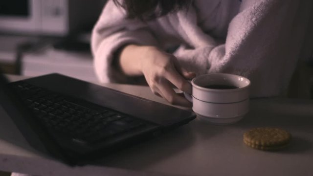 girl in a bathrobe drinking coffee and working on the netbook