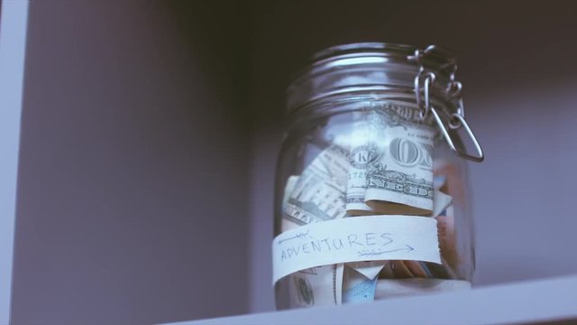 RL DOLLY Caucasian male putting a glass jar with his savings for future travels. 4K UHD RAW edited footage