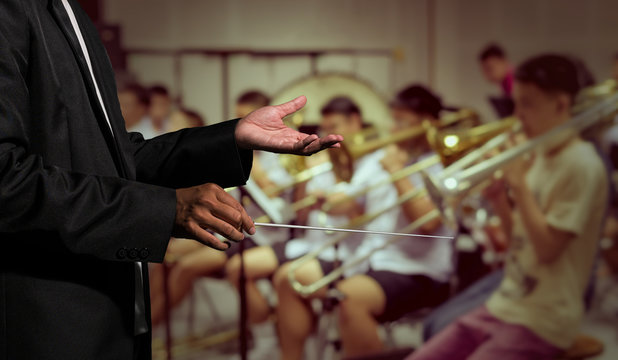 Orchestra conductor hands leading over the Abstract blurred phot