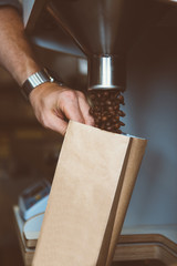 man filling paper bag with coffee beans - 124821703