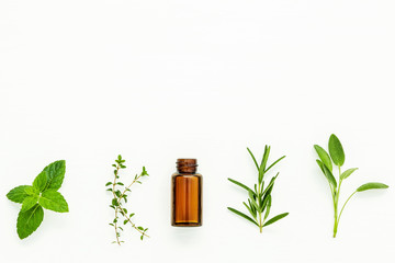 Bottle of essential oil with  fresh herbal sage, rosemary, lemon