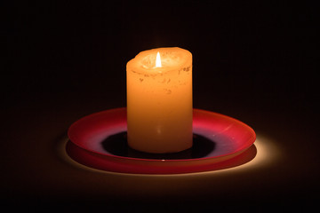 candle on red plate with flame