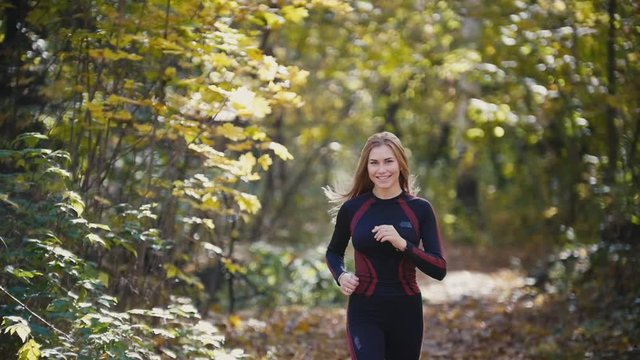 Young active female athlete exercising outdoor autumn park. Girl smiling, hair waving, Healthy women, slow-motion