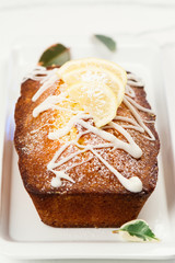 Lemon loaf with white glaze on wooden background