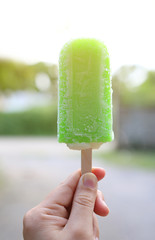 Woman hand holding lemon vanilla popsicle.