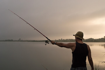 Fisherman fishing on the bank of the lake at sunrise