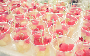 Fruit Salad arranged in plastic cups on a market stall focus on middle front cup.