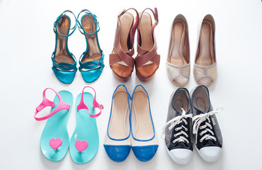 Every girl needs. Overhead of essentials for modern young woman. Different ladies shoes on white wooden background.