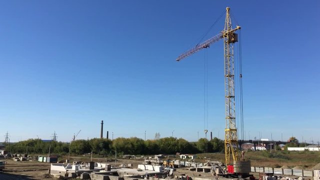A high construction crane working in industrial area with construction side during the sunny day. Black bird interfering. hd video (high definition).