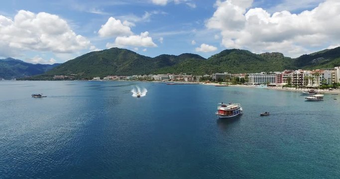 Camera moves forward near the yacht at the pier on the sea in Turkey, Marmaris. Focus on  speedboat. Beautiful mountain and sea landscape. Aerial view shooting with drone DJI Inspire1, 4k video. 