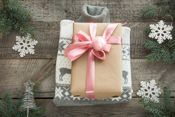 Christmas gift with pink ribbon and grey sweater on wooden surface. Overhead view. Christmas consept.