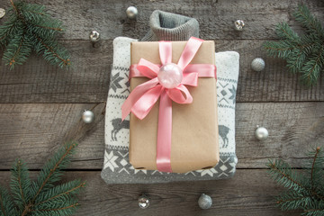 Christmas gift with pink ribbon and grey sweater on wooden surface. Overhead view. Christmas consept.