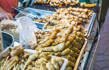Evening street food in Bangkok, Thailand : Grilled squid on gridiron in evening street market, Squid barbecue in Thai street food market